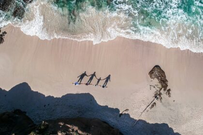 a-group-of-people-standing-on-top-of-a-sandy-beach